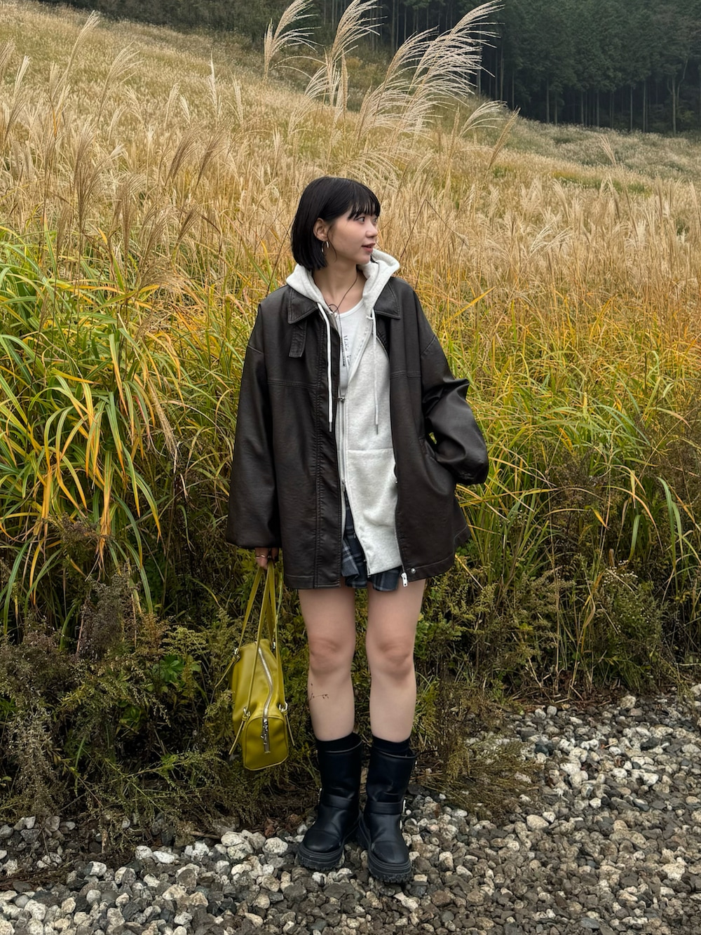 グレー系のパーカー、グレー系のスカート、ブラック系のブーツを着用したレディースの秋コーディネートの2枚目の写真