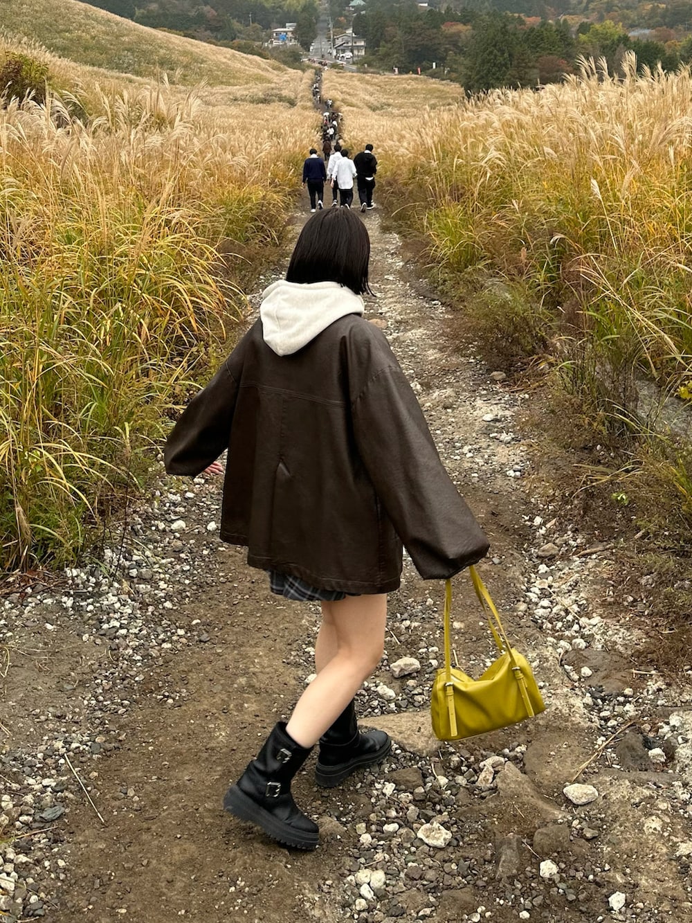 グレー系のパーカー、グレー系のスカート、ブラック系のブーツを着用したレディースの秋コーディネートの4枚目の写真