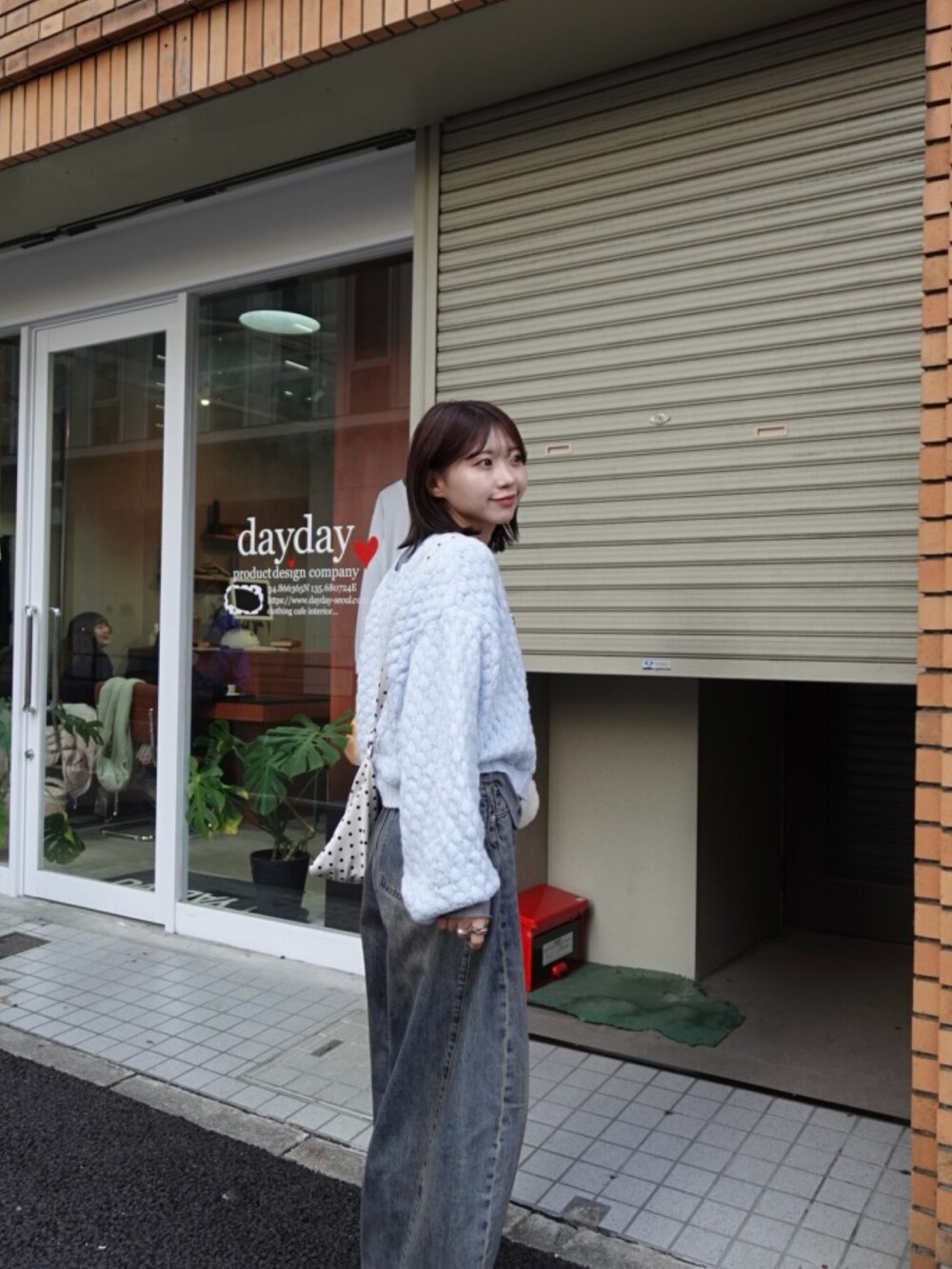 ブルー系のカーディガン/ボレロ、ブルー系のデニムパンツ、ホワイト系のショルダーバッグを着用したレディースの冬コーディネートの2枚目の写真