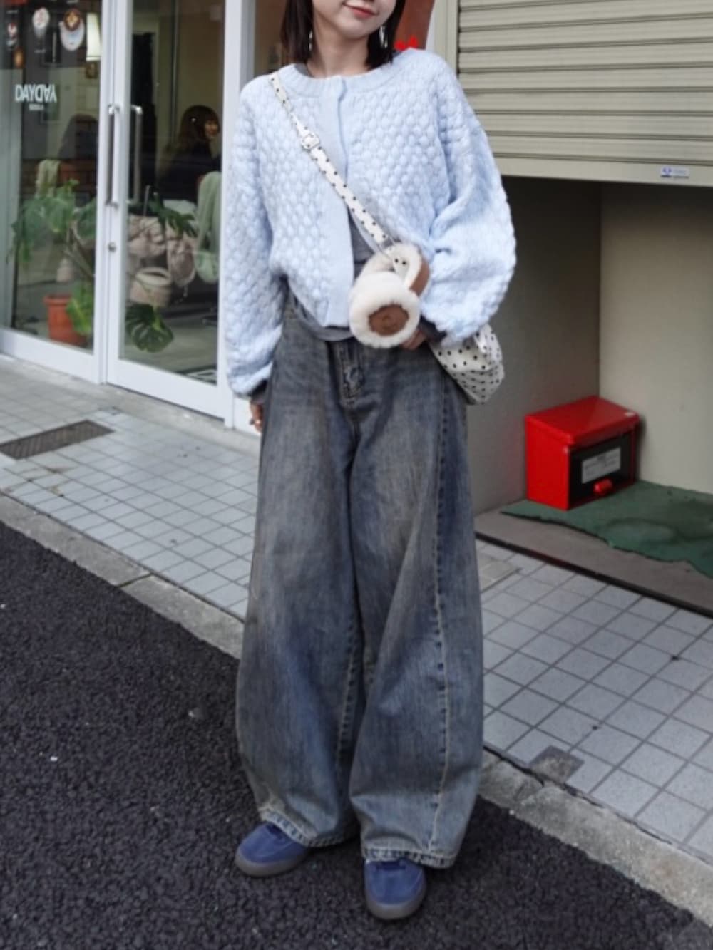 ブルー系のカーディガン/ボレロ、ブルー系のデニムパンツ、ホワイト系のショルダーバッグを着用したレディースの冬コーディネートの3枚目の写真
