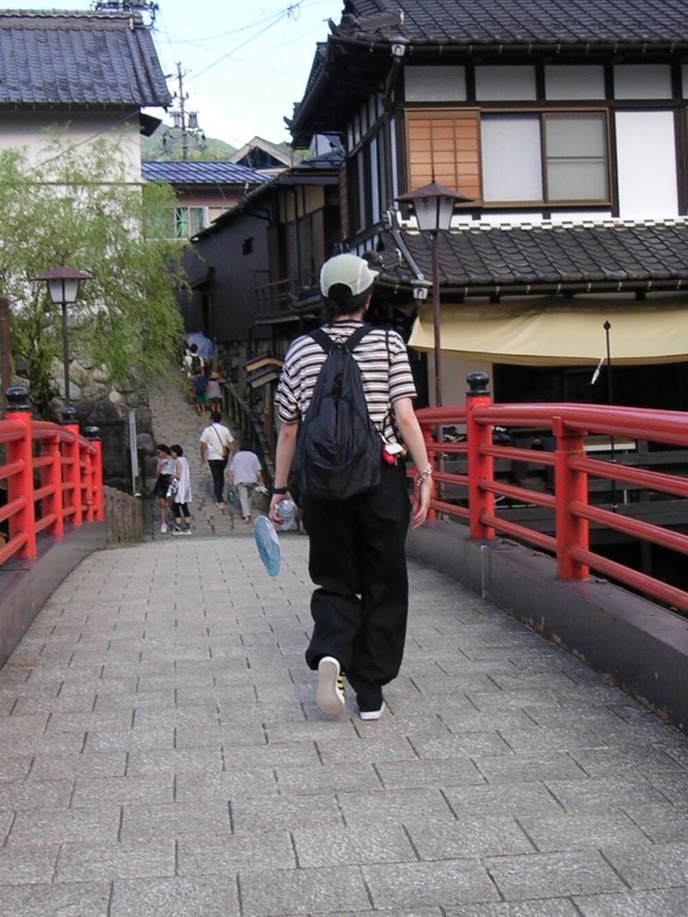 ブルー系のトップス、ブラック系のパンツ、グリーン系の帽子を着用したレディースの夏コーディネートの2枚目の写真