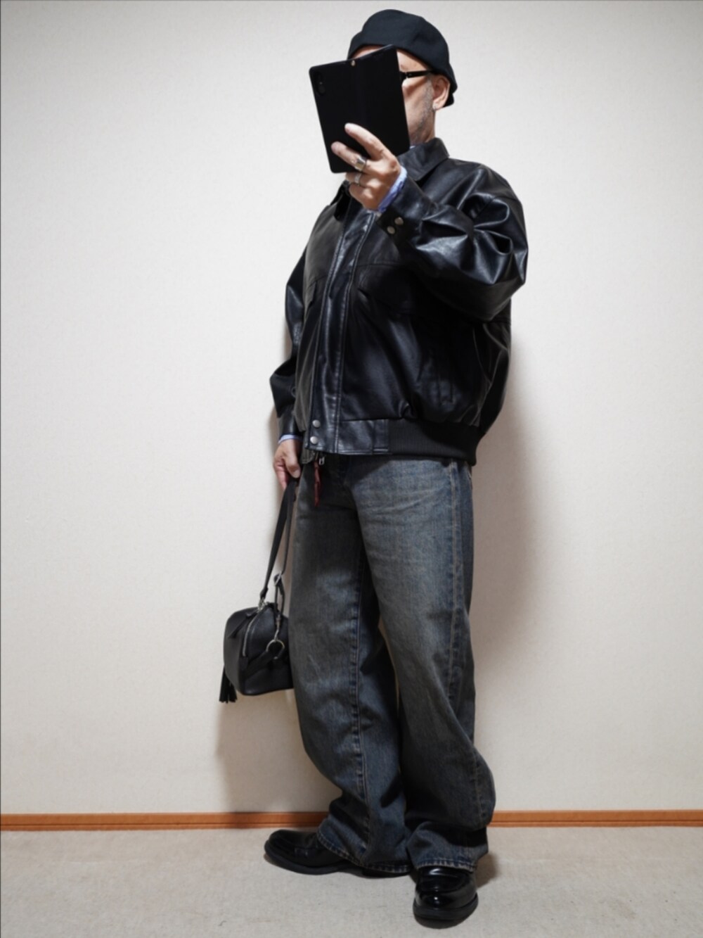 ブラック系のシューズ、ブルー系のデニムパンツ、ブラック系のショルダーバッグを着用したメンズの秋コーディネートの2枚目の写真
