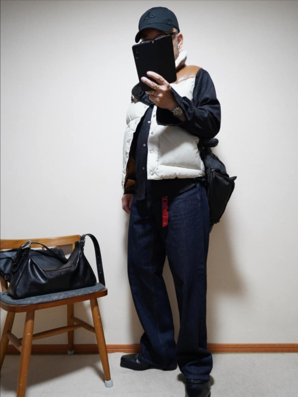 ブラック系のブーツ、ブルー系のデニムパンツ、その他のダウンベストを着用したメンズの秋コーディネートの2枚目の写真