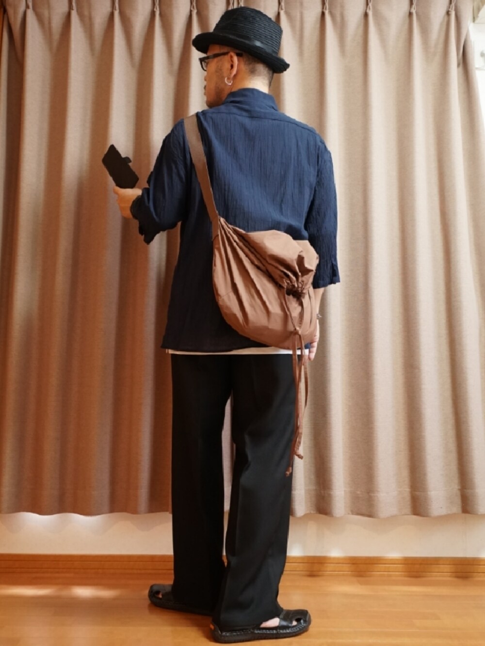 ブラック系のサンダル、ブラック系のパンツ、ホワイト系のタンクトップを着用したメンズの夏コーディネートの3枚目の写真