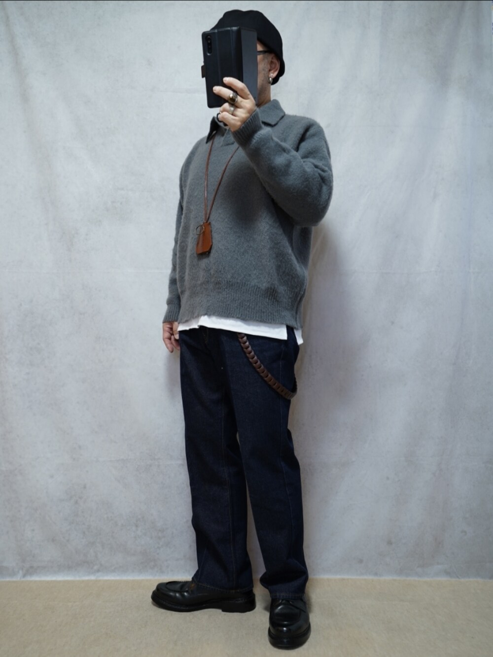 ブラック系のシューズ、ブルー系のデニムパンツ、グレー系のニット/セーターを着用したメンズの春コーディネートの2枚目の写真