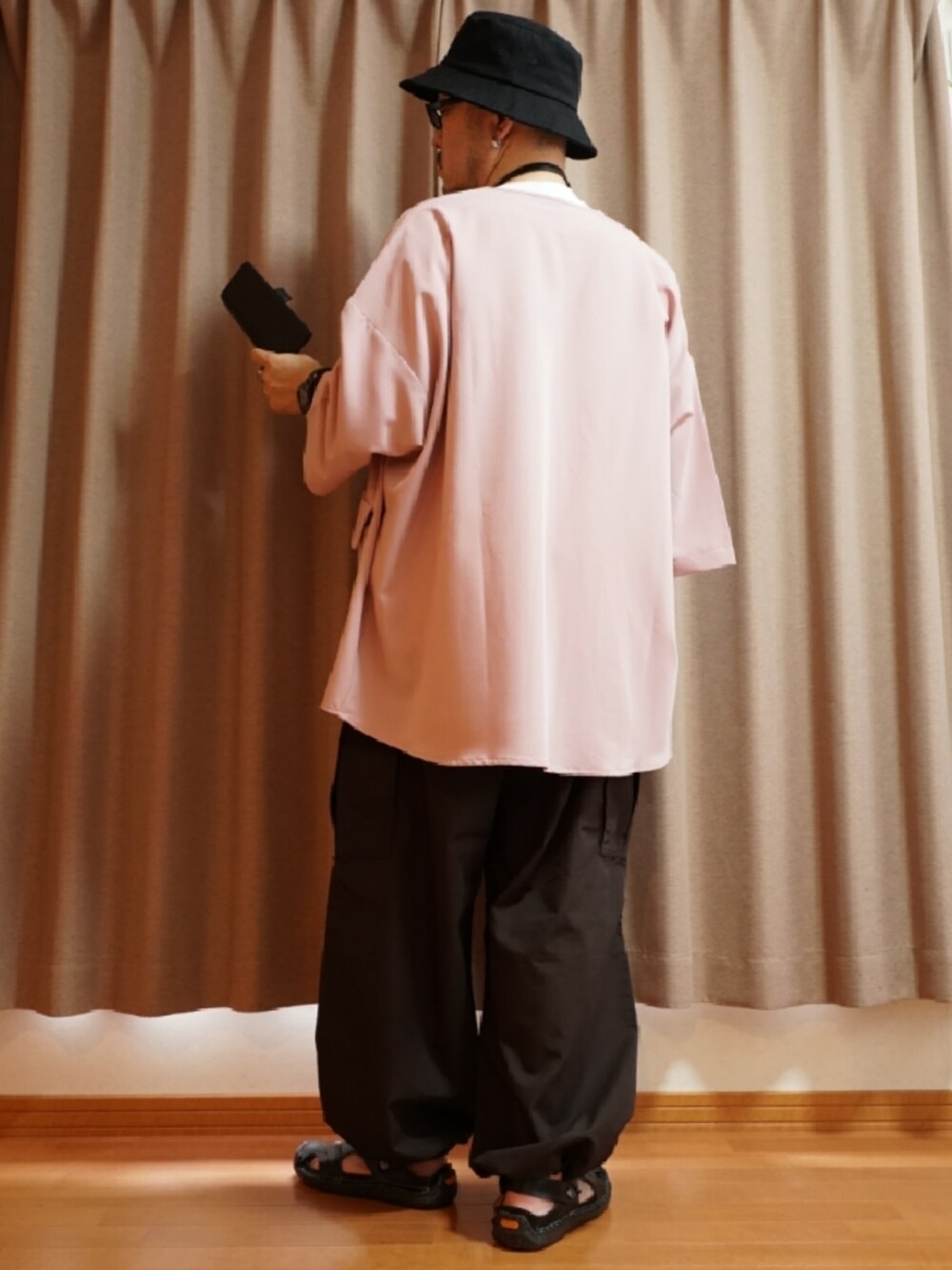 ブラック系のサンダル、ブラウン系のパンツ、ホワイト系のタンクトップを着用したメンズの夏コーディネートの3枚目の写真