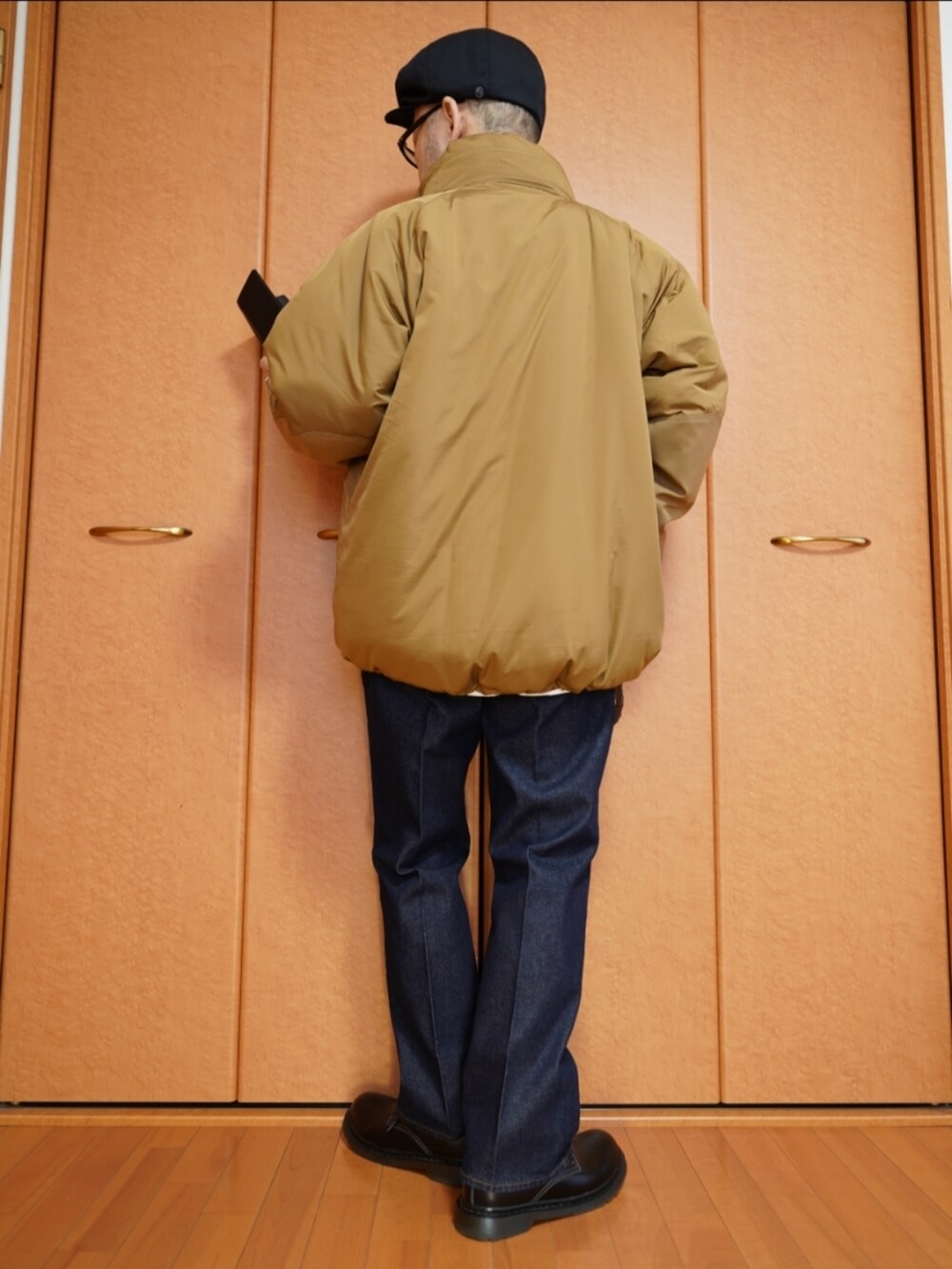 ブラック系のシューズ、ブルー系のデニムパンツ、ベージュ系のミリタリージャケットを着用したメンズの秋コーディネートの3枚目の写真