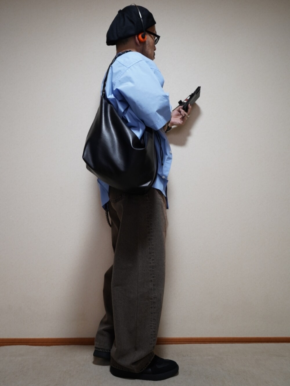 ブラック系のスニーカー、ブラウン系のデニムパンツ、ブラック系のショルダーバッグを着用したメンズの夏コーディネートの5枚目の写真