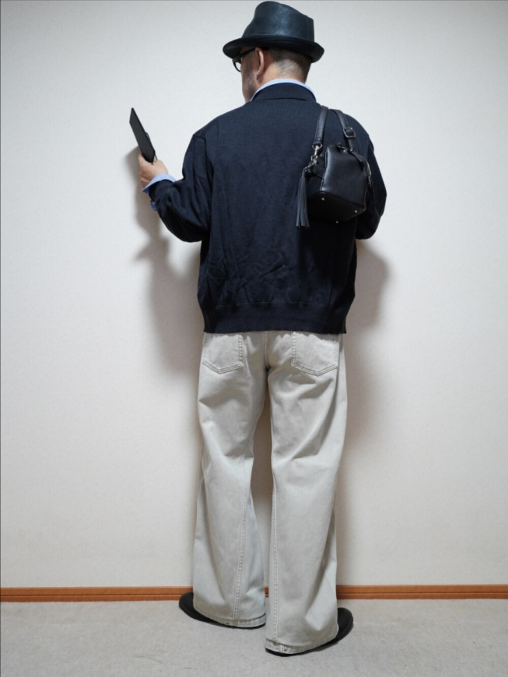 ブラック系のスリッポン、ベージュ系のデニムパンツ、ブラック系のショルダーバッグを着用したメンズの秋コーディネートの4枚目の写真