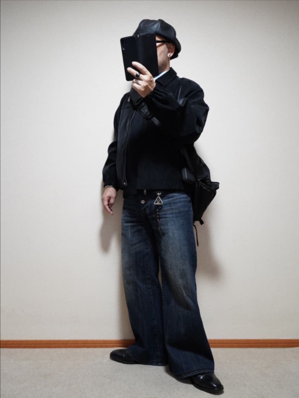 ブラック系のドレスシューズ、ブルー系のデニムパンツ、ブラック系のニット/セーターを着用したメンズの冬コーディネートの2枚目の写真