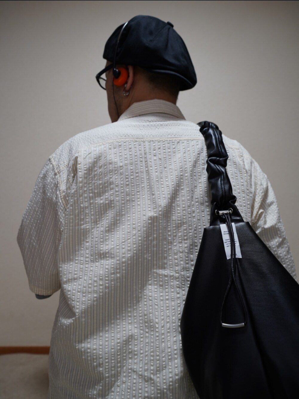 ブラック系のシューズ、ブルー系のデニムパンツ、ブラック系のショルダーバッグを着用したメンズの夏コーディネートの3枚目の写真