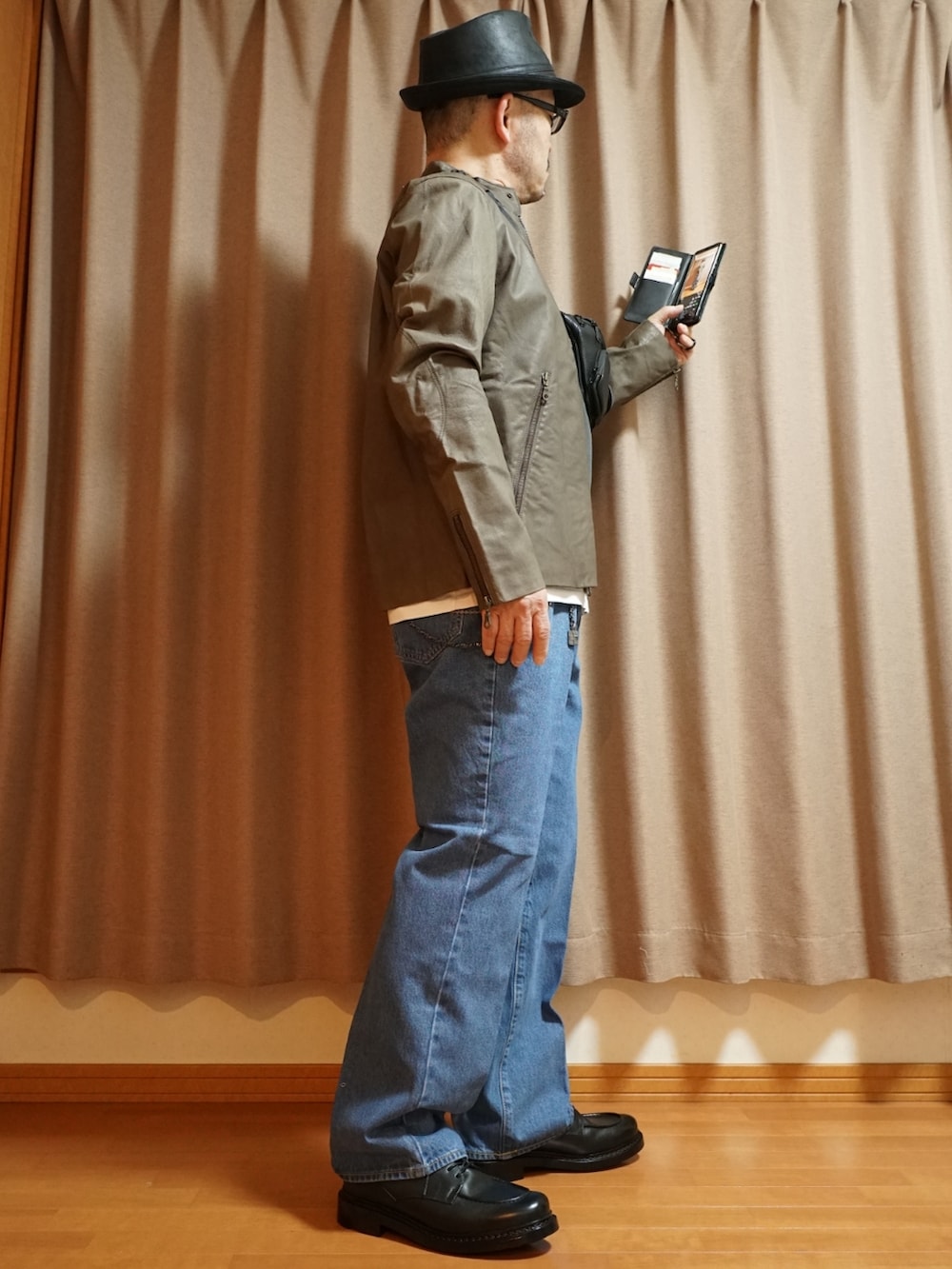ブラック系のシューズ、ブルー系のデニムパンツ、ブラウン系のライダースジャケットを着用したメンズの夏コーディネートの4枚目の写真