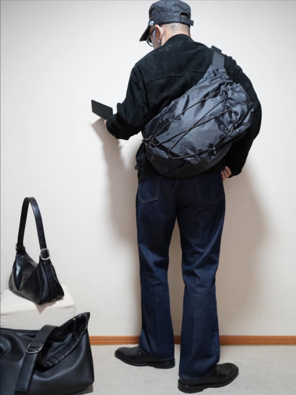 ブラック系のドレスシューズ、ブルー系のデニムパンツ、ブラック系のブルゾンを着用したメンズの春コーディネートの4枚目の写真