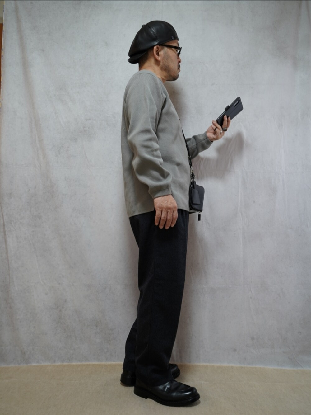 グレー系のパンツ、ブラック系のショルダーバッグ、グレー系のニット/セーターを着用したメンズの春コーディネートの4枚目の写真
