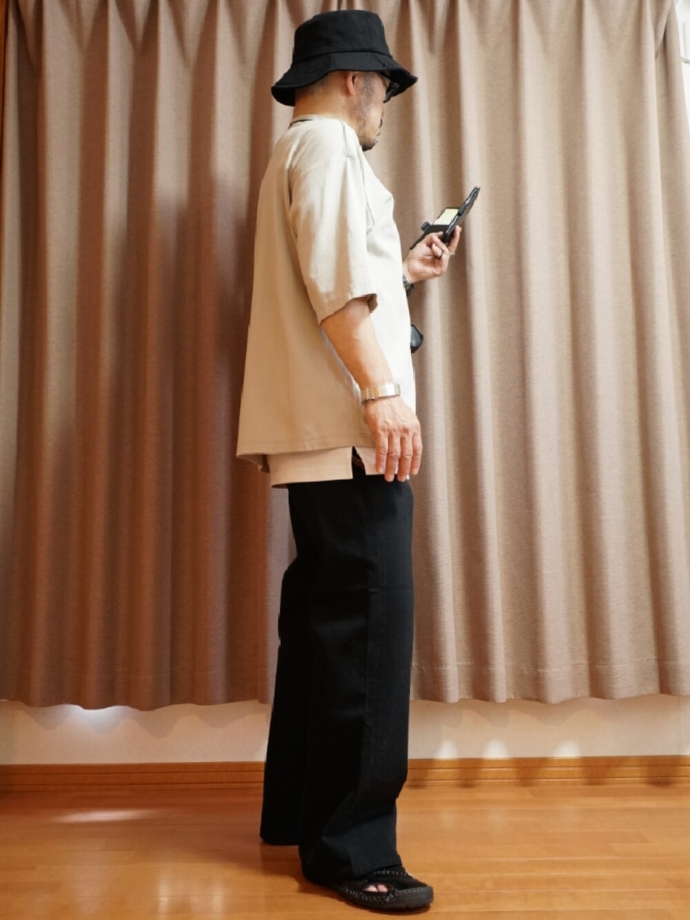 ブラック系のサンダル、グレー系のデニムパンツ、ホワイト系のタンクトップを着用したメンズの夏コーディネートの4枚目の写真