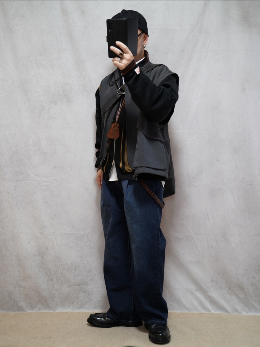 ブラック系のシューズ、ブルー系のデニムパンツ、ブラック系のカーディガン/ボレロを着用したメンズの春コーディネートの2枚目の写真