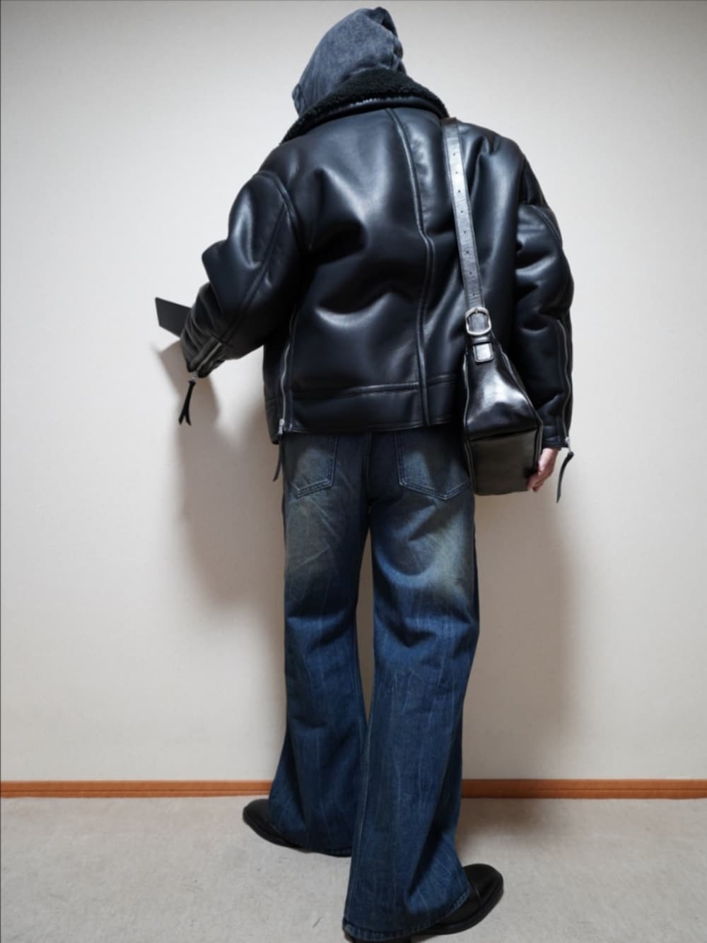 ブルー系のデニムパンツ、ブラック系のショルダーバッグ、ブラック系のパーカーを着用したメンズの冬コーディネートの4枚目の写真