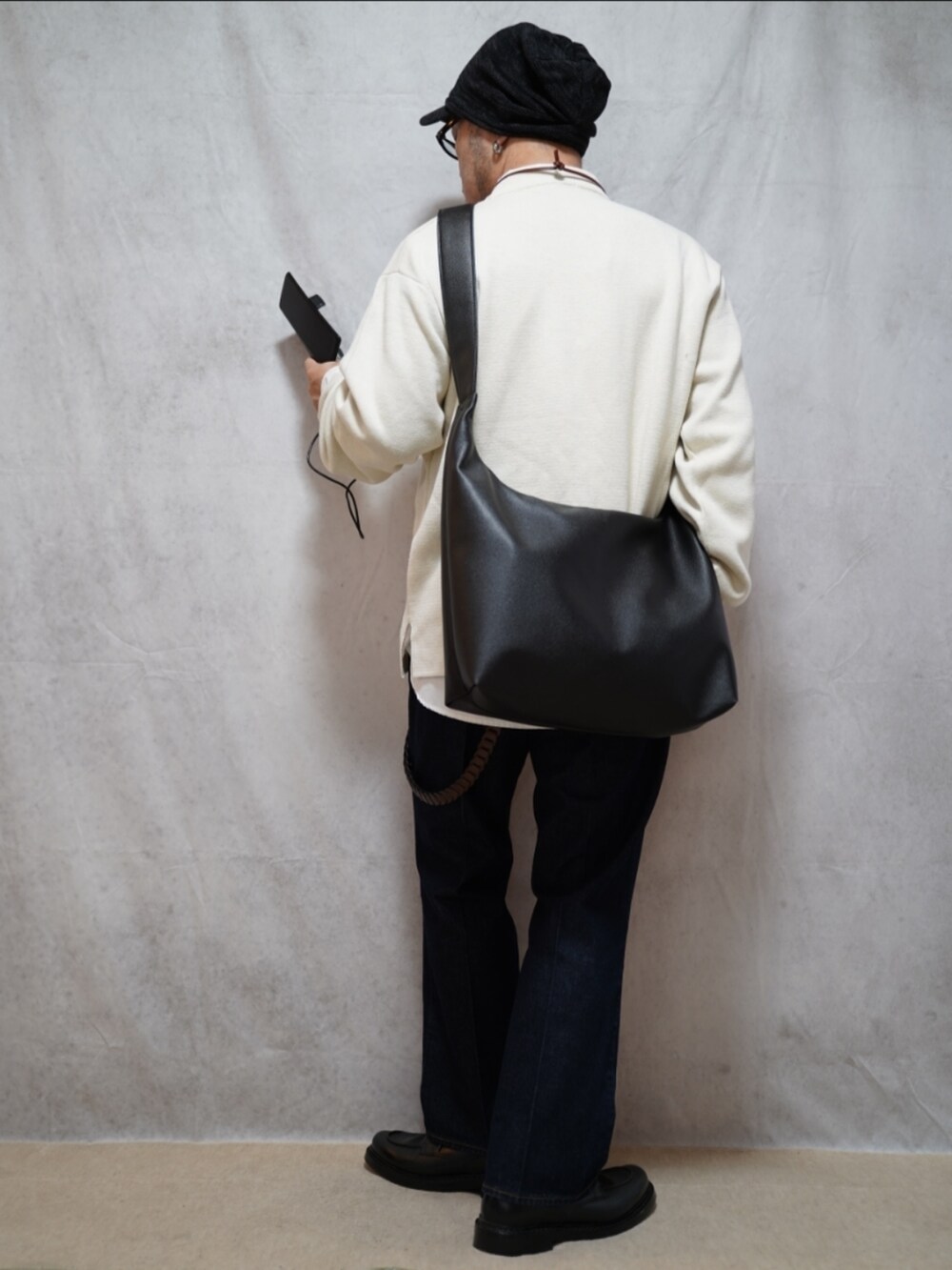 ブラック系のシューズ、ホワイト系のニット/セーター、ブルー系のデニムパンツを着用したメンズの春コーディネートの3枚目の写真