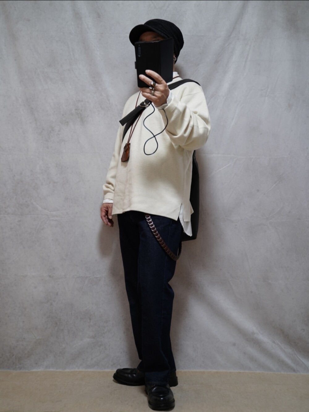 ブラック系のシューズ、ホワイト系のニット/セーター、ブルー系のデニムパンツを着用したメンズの春コーディネートの2枚目の写真