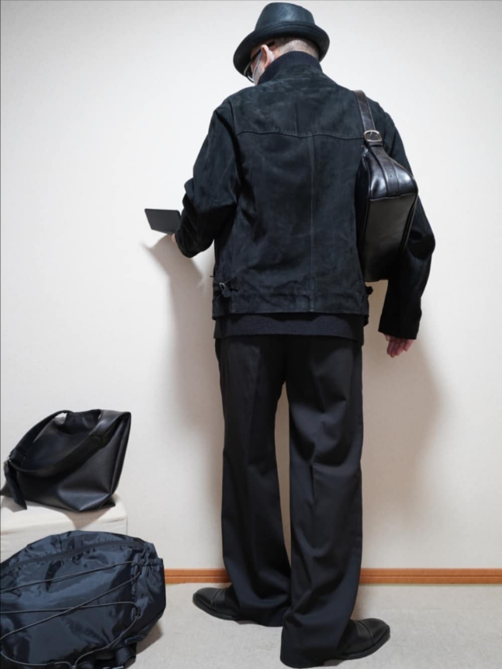 ブラック系のドレスシューズ、ブラック系のスラックス、ブラック系のショルダーバッグを着用したメンズの春コーディネートの4枚目の写真