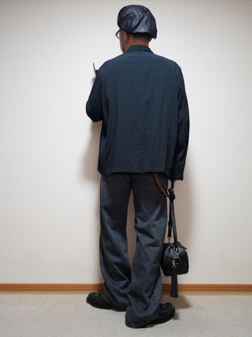 ブラック系のシューズ、ブルー系のデニムパンツ、ブラック系のショルダーバッグを着用したメンズの春コーディネートの4枚目の写真