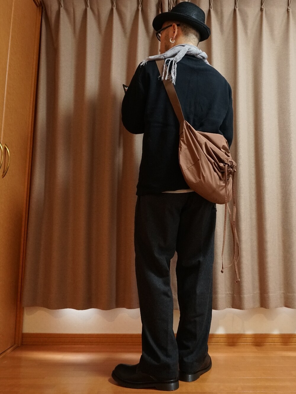 ブラック系のシューズ、グレー系のパンツ、ピンク系のバッグを着用したメンズの秋コーディネートの2枚目の写真