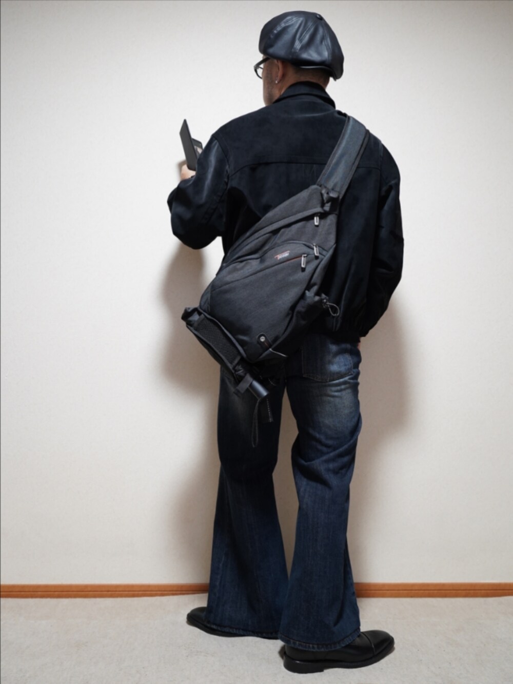 ブラック系のドレスシューズ、ブルー系のデニムパンツ、ブラック系のニット/セーターを着用したメンズの冬コーディネートの3枚目の写真