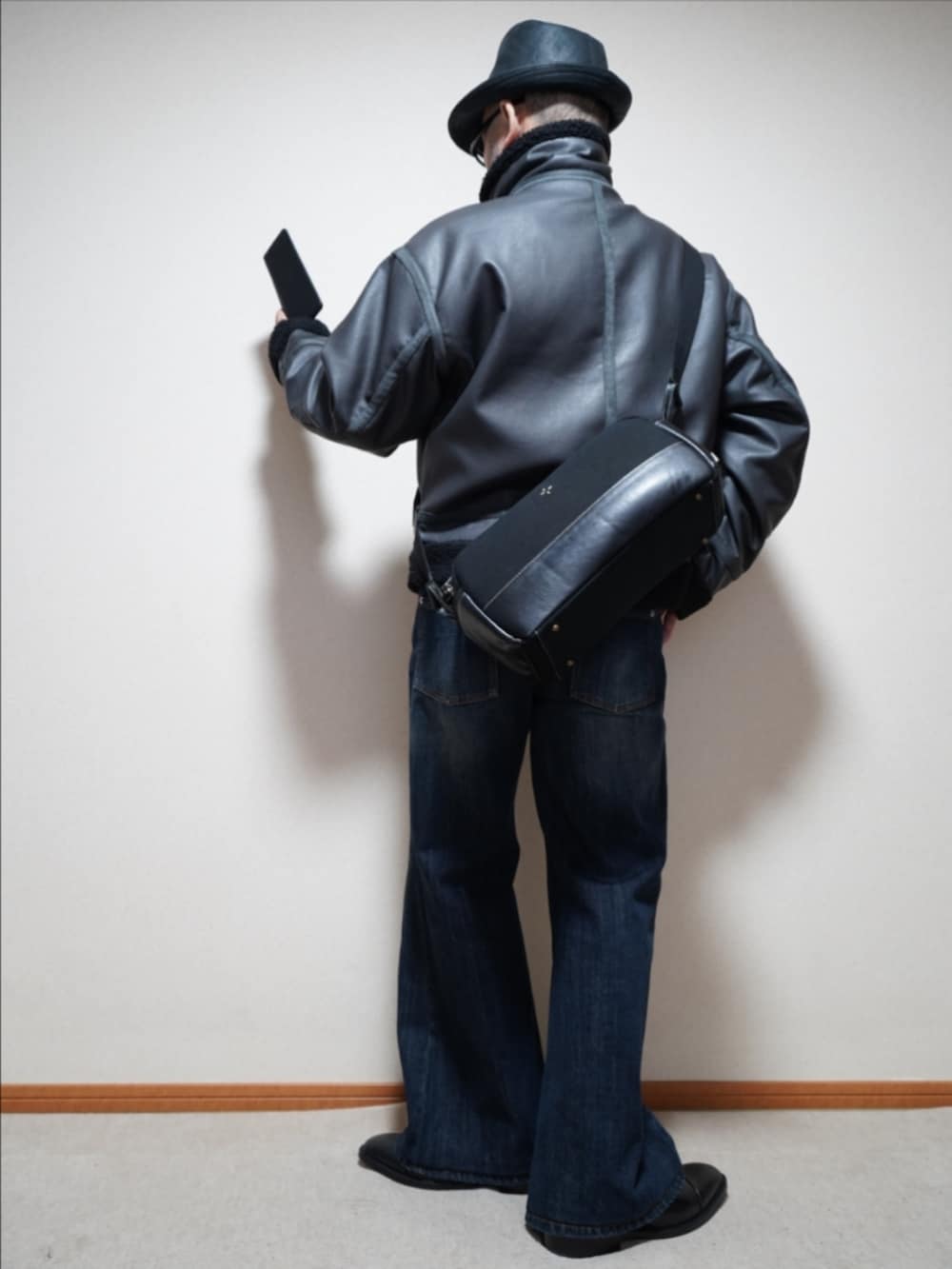 ブラック系のドレスシューズ、ブルー系のデニムパンツ、グレー系のブルゾンを着用したメンズの冬コーディネートの3枚目の写真