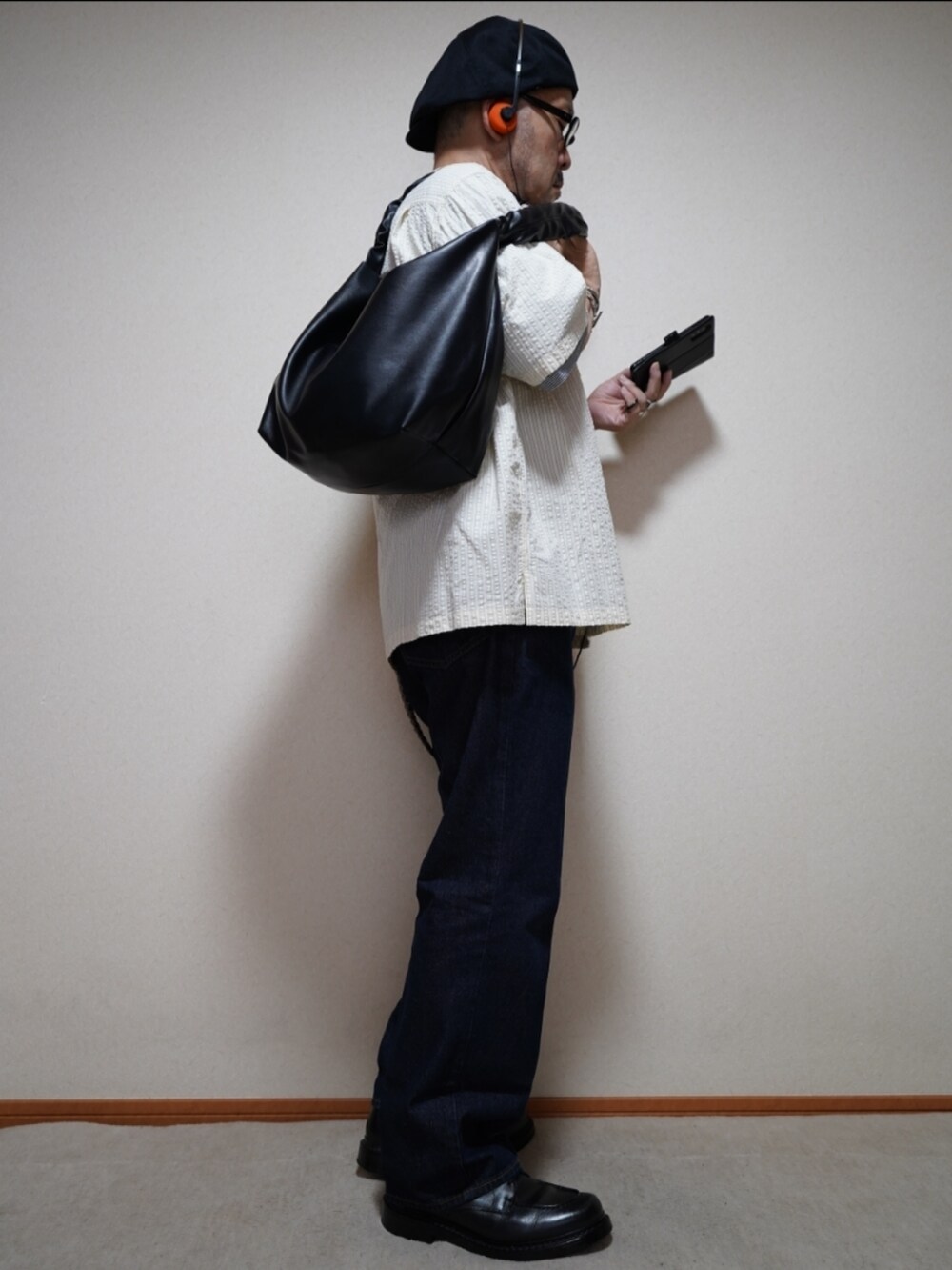 ブラック系のシューズ、ブルー系のデニムパンツ、ブラック系のショルダーバッグを着用したメンズの夏コーディネートの5枚目の写真