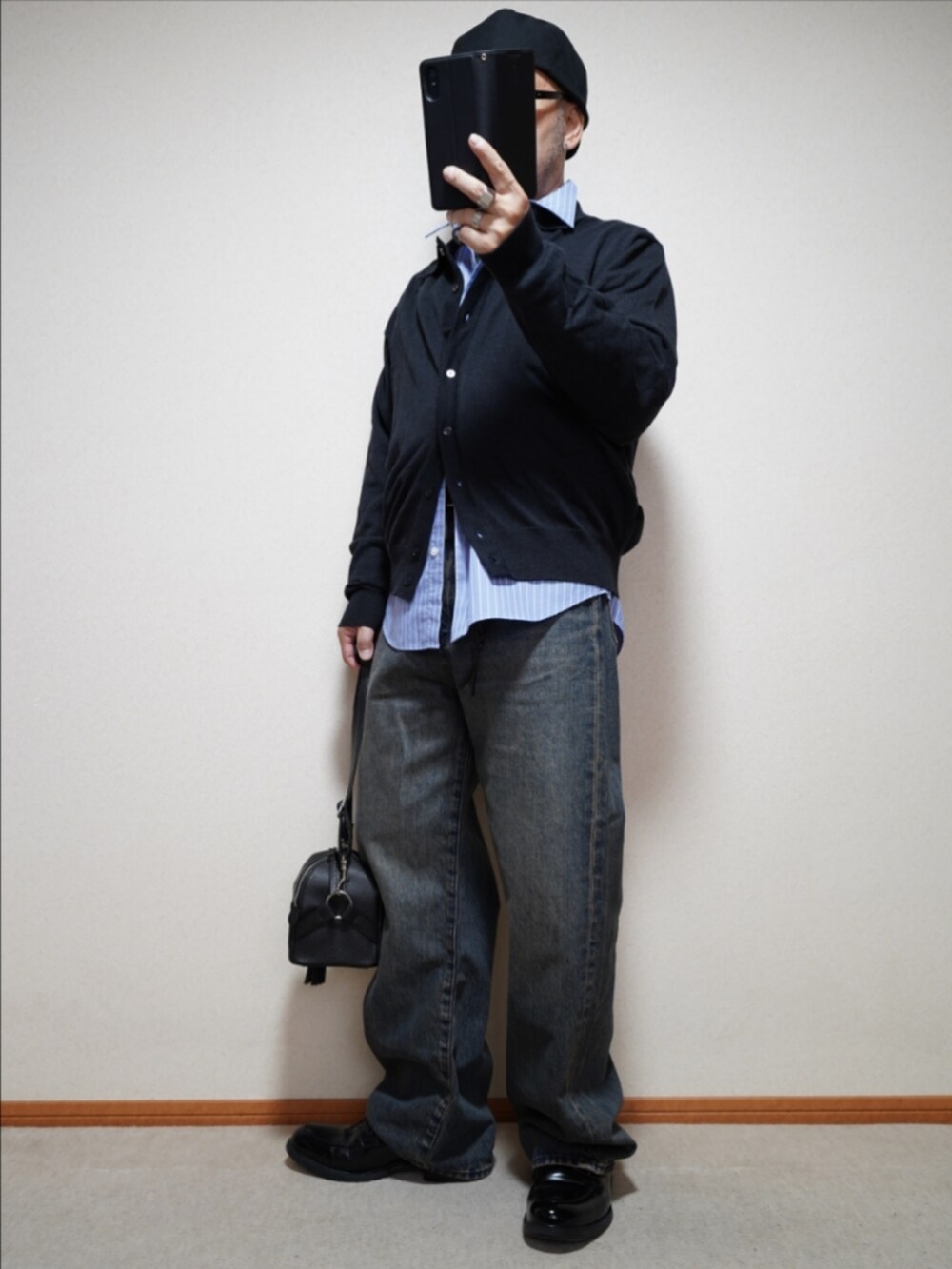 ブラック系のシューズ、ブルー系のデニムパンツ、ブラック系のショルダーバッグを着用したメンズの秋コーディネートの2枚目の写真