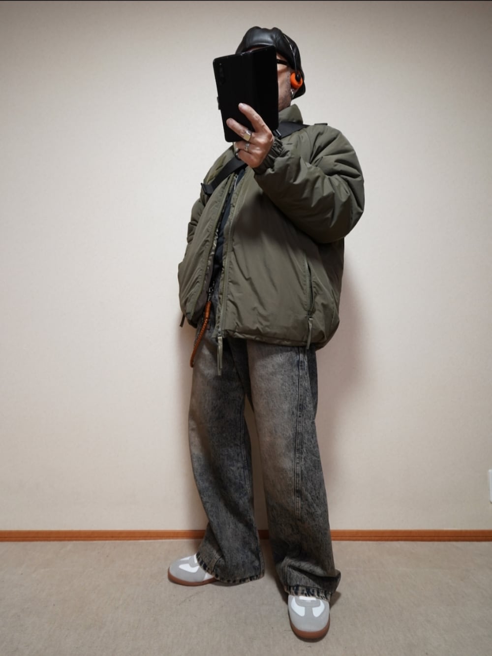 ホワイト系のスニーカー、ブルー系のデニムパンツ、グリーン系のミリタリージャケットを着用したメンズの冬コーディネートの2枚目の写真