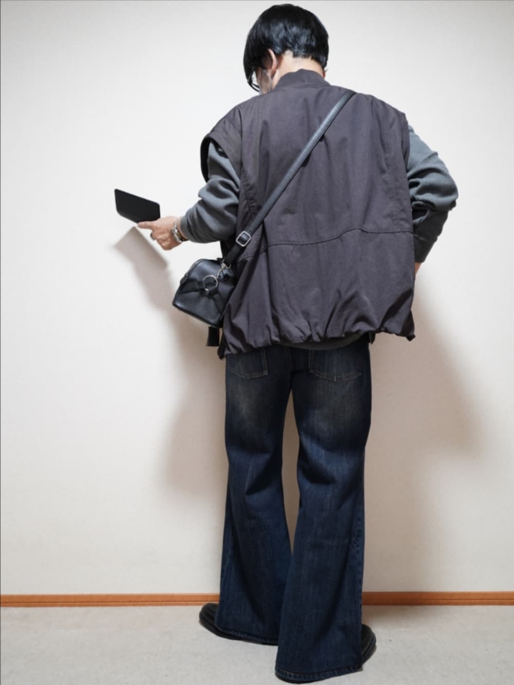 ブラック系のシューズ、ブルー系のデニムパンツ、ブラック系のショルダーバッグを着用したメンズの秋コーディネートの4枚目の写真