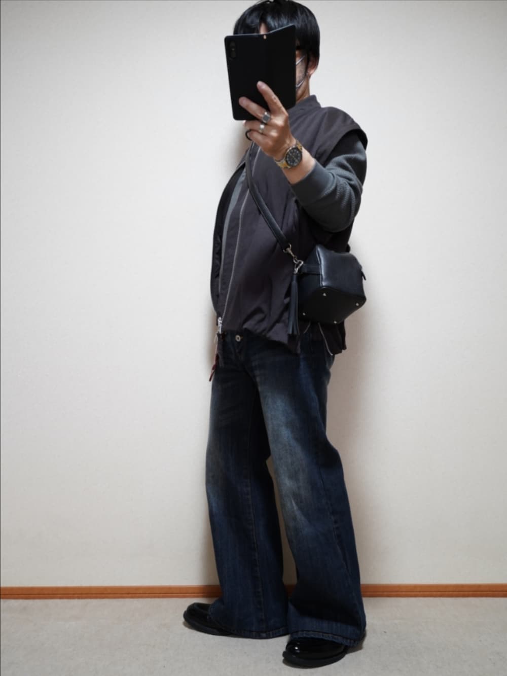 ブラック系のシューズ、ブルー系のデニムパンツ、ブラック系のショルダーバッグを着用したメンズの秋コーディネートの2枚目の写真