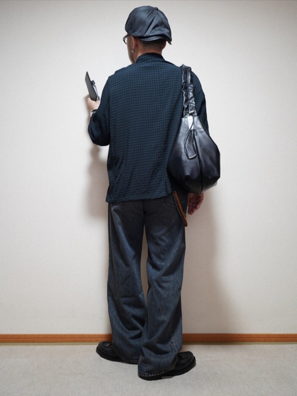 ブラック系のシューズ、ブルー系のデニムパンツ、ブラック系のショルダーバッグを着用したメンズの春コーディネートの4枚目の写真