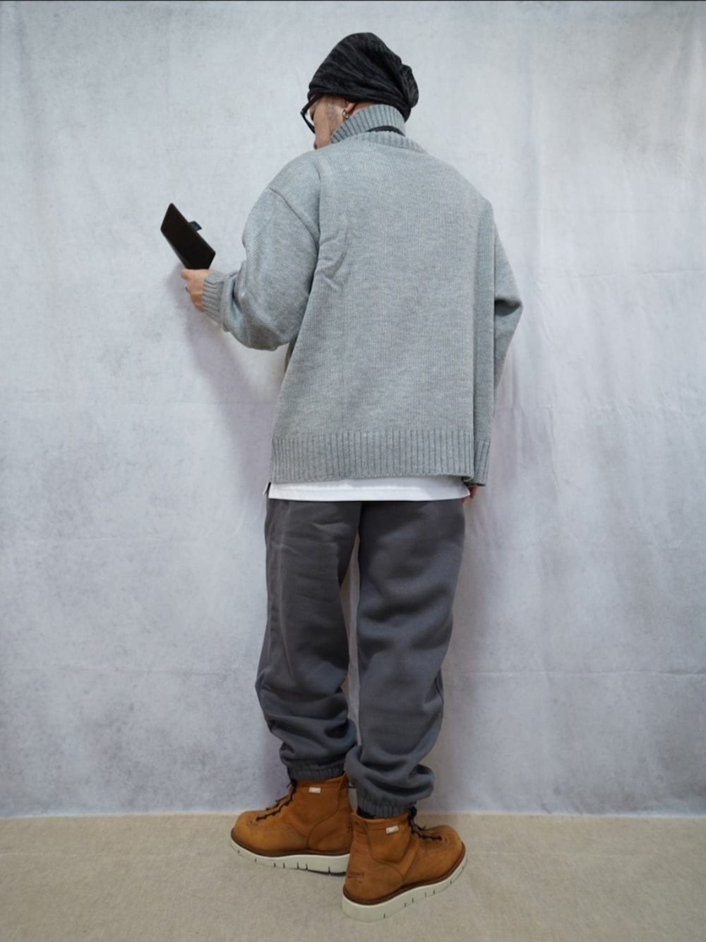 ブラウン系のブーツ、グレー系のスウェットパンツ、グレー系のニット/セーターを着用したメンズの冬コーディネートの2枚目の写真
