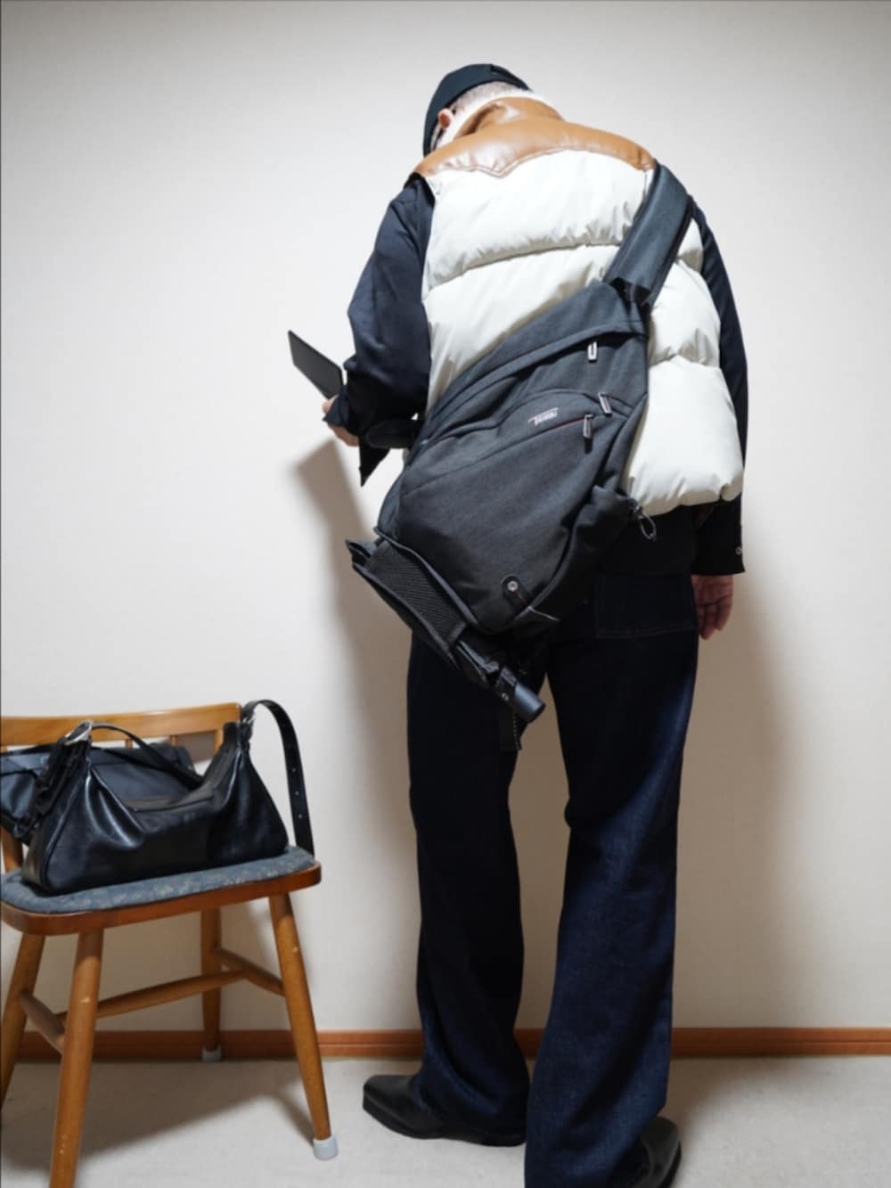 ブラック系のブーツ、ブルー系のデニムパンツ、その他のダウンベストを着用したメンズの秋コーディネートの3枚目の写真