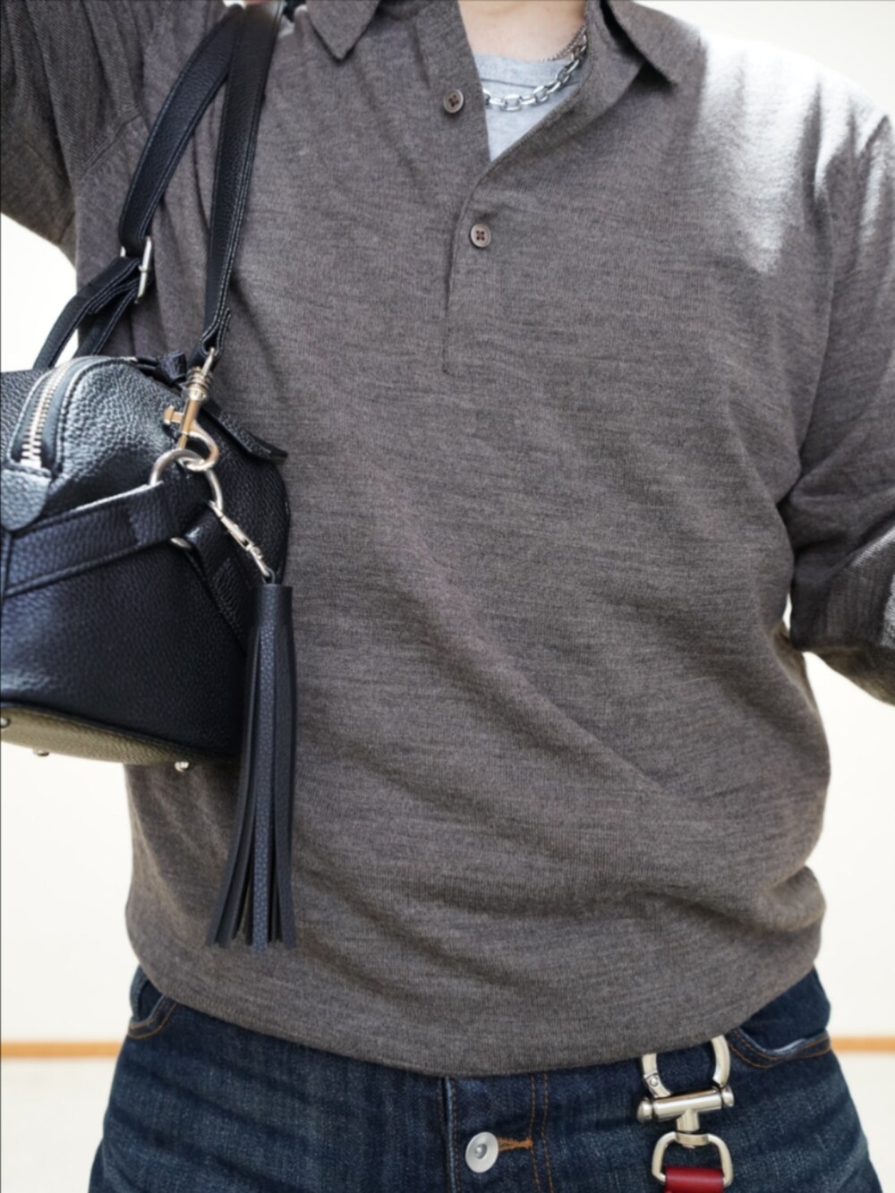 ブラック系のスニーカー、ブルー系のデニムパンツ、ブラック系のショルダーバッグを着用したメンズの秋コーディネートの3枚目の写真