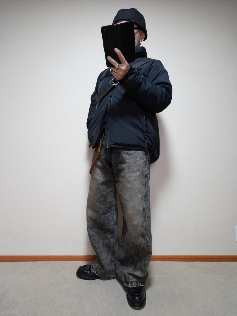 ブラック系のシューズ、ブルー系のデニムパンツ、ブラック系のダウンジャケット/コートを着用したメンズの秋コーディネートの2枚目の写真