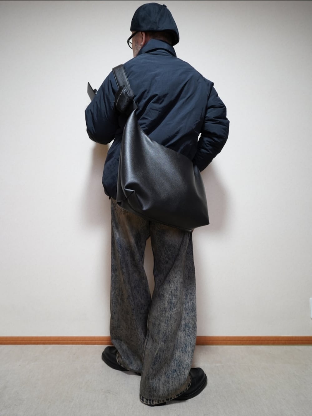 ブラック系のシューズ、ブルー系のデニムパンツ、ブラック系のダウンジャケット/コートを着用したメンズの秋コーディネートの3枚目の写真