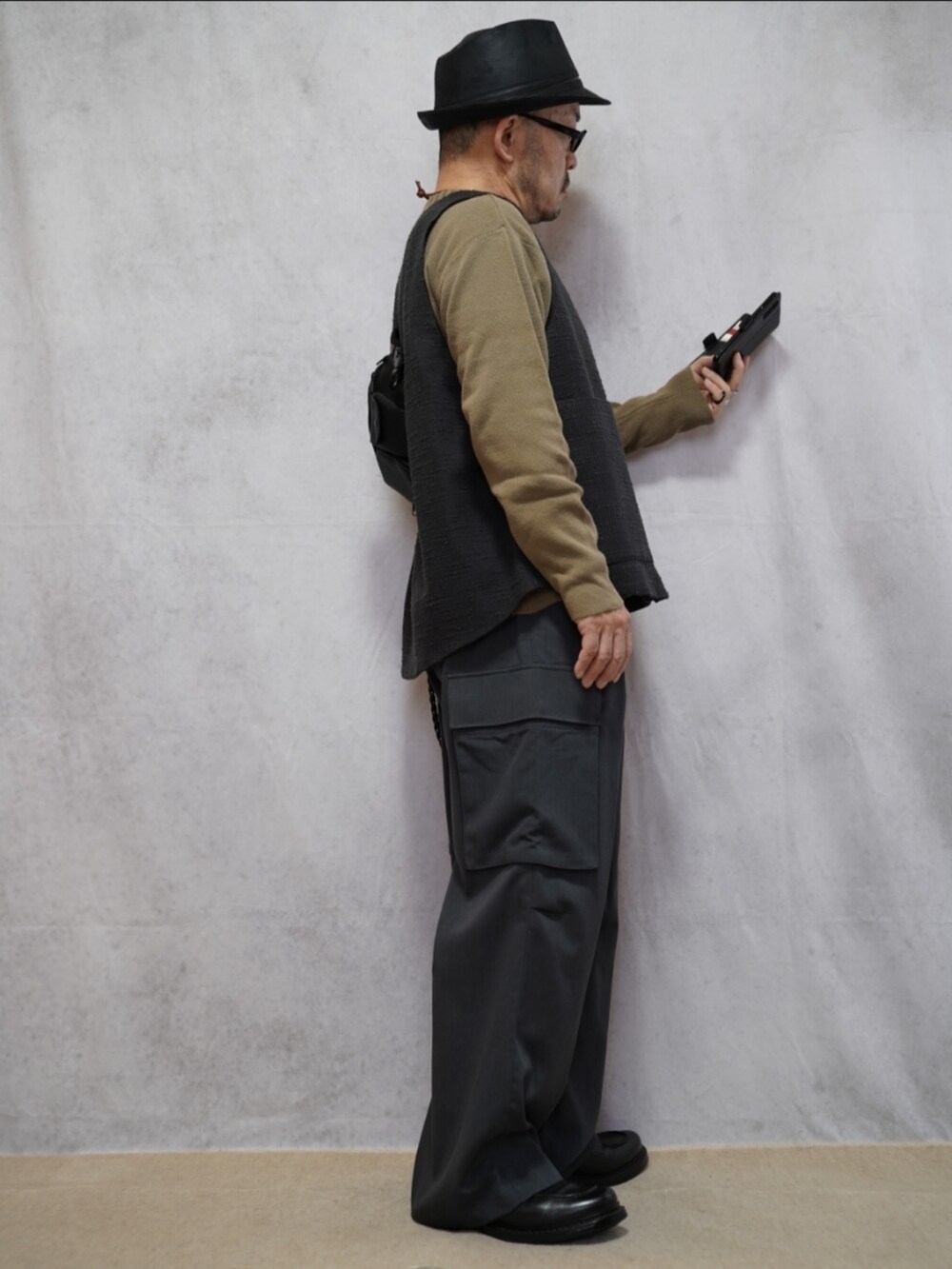 ブラック系のシューズ、グレー系のカーゴパンツ、ベージュ系のニット/セーターを着用したメンズの春コーディネートの4枚目の写真