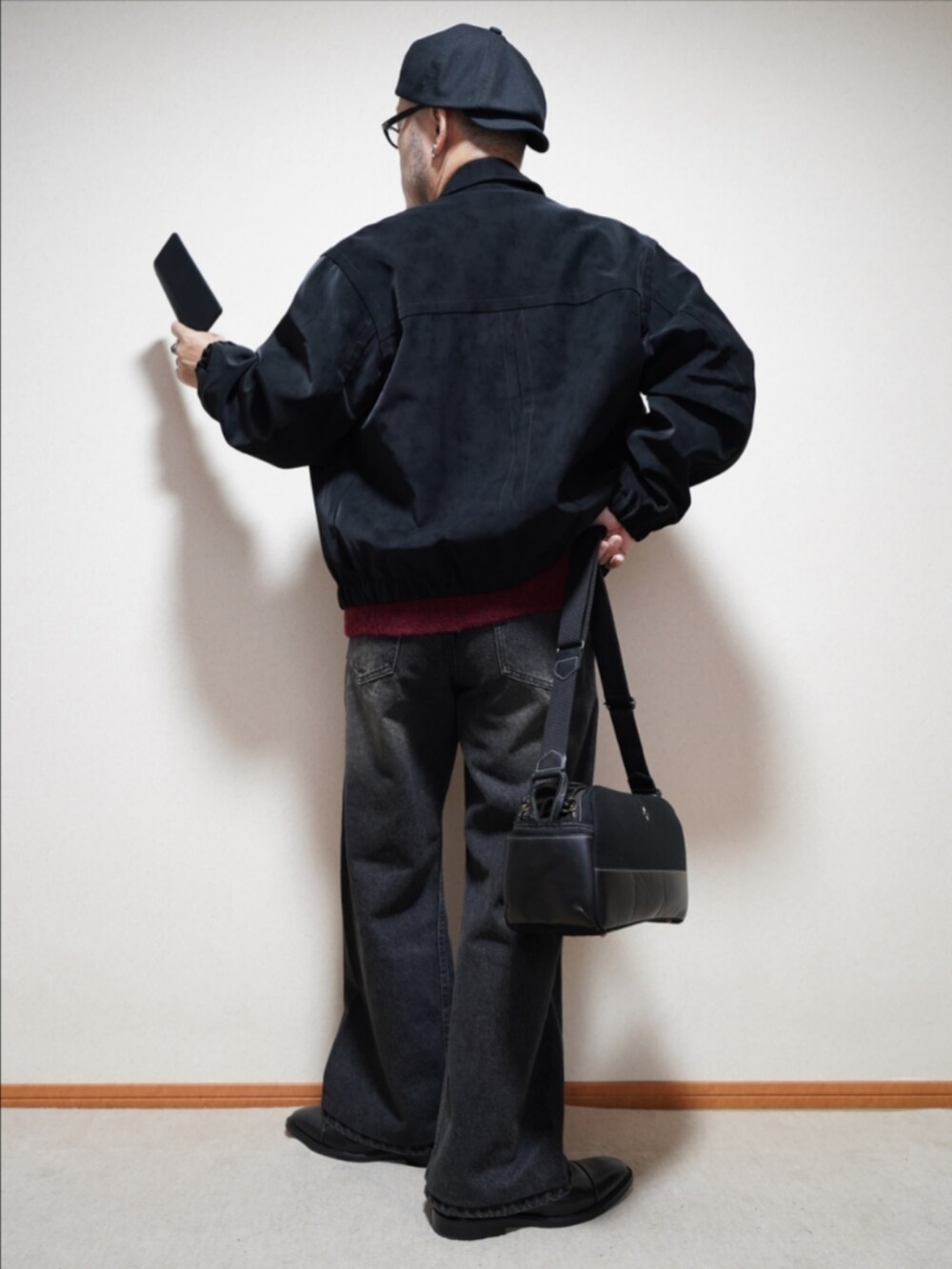ブラック系のドレスシューズ、ブラック系のデニムパンツ、レッド系のカーディガン/ボレロを着用したメンズの冬コーディネートの3枚目の写真
