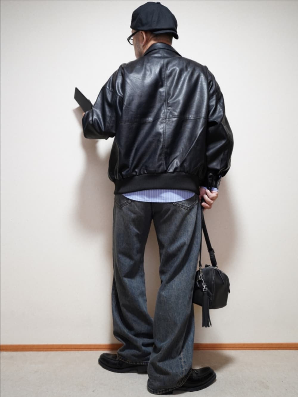 ブラック系のシューズ、ブルー系のデニムパンツ、ブラック系のショルダーバッグを着用したメンズの秋コーディネートの4枚目の写真