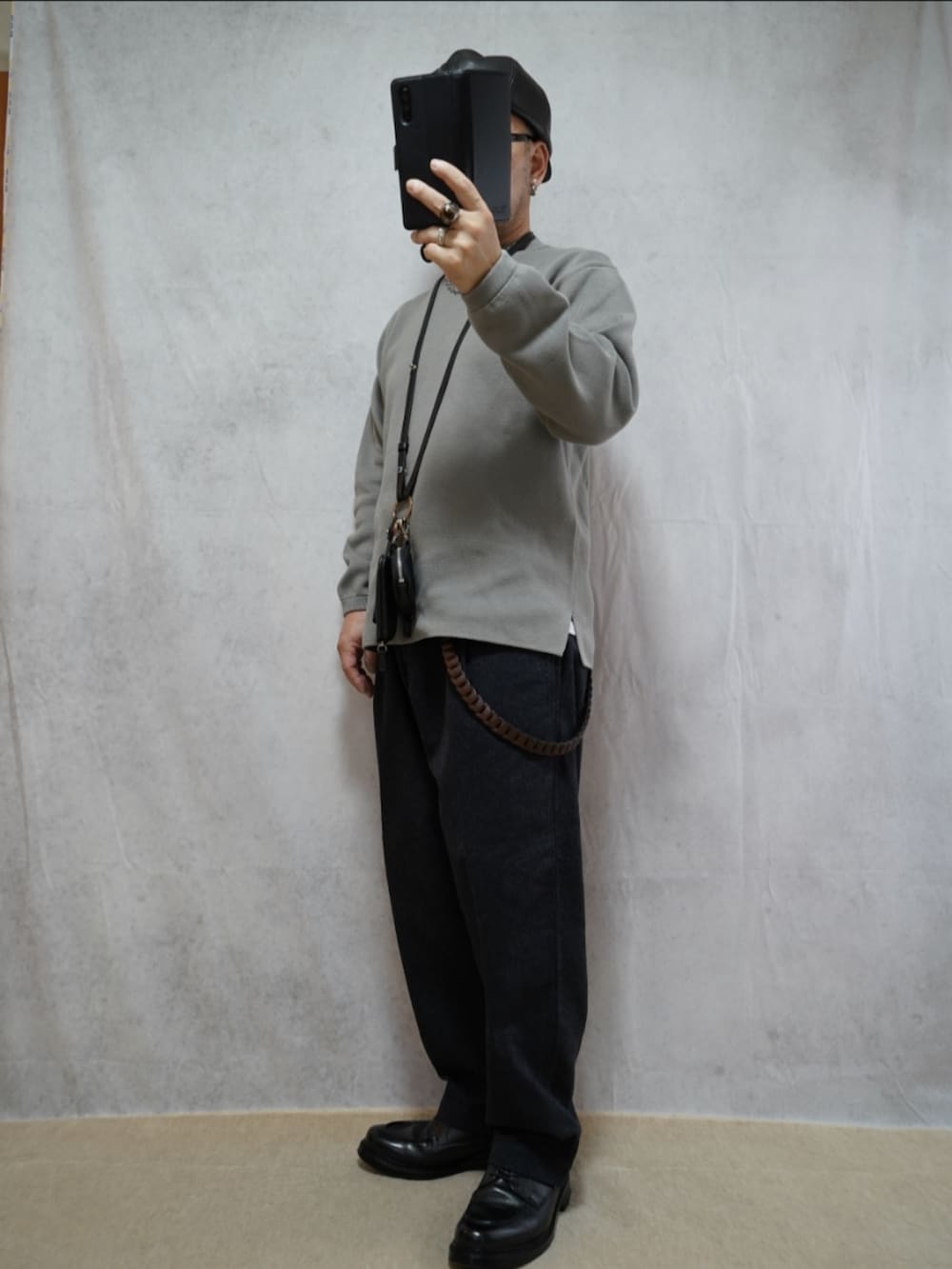 グレー系のパンツ、ブラック系のショルダーバッグ、グレー系のニット/セーターを着用したメンズの春コーディネートの2枚目の写真