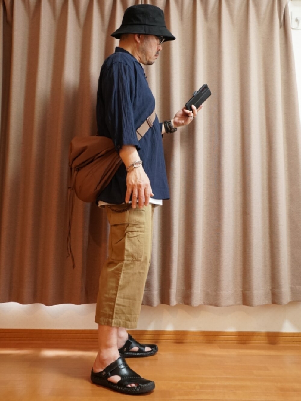 ブラック系のサンダル、ブラウン系のパンツ、ホワイト系のタンクトップを着用したメンズの夏コーディネートの4枚目の写真