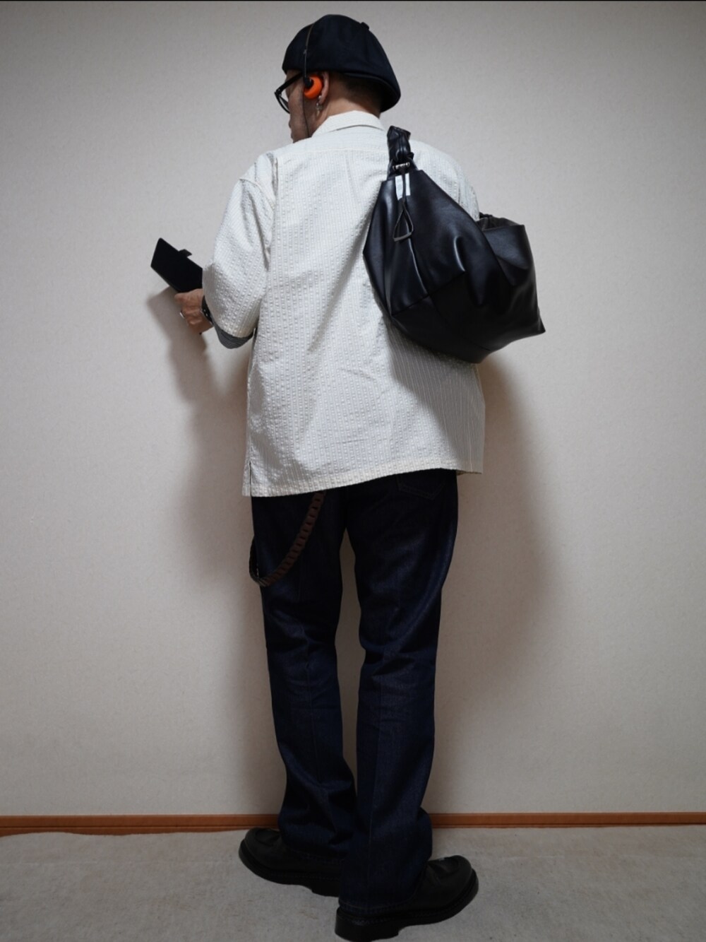 ブラック系のシューズ、ブルー系のデニムパンツ、ブラック系のショルダーバッグを着用したメンズの夏コーディネートの4枚目の写真