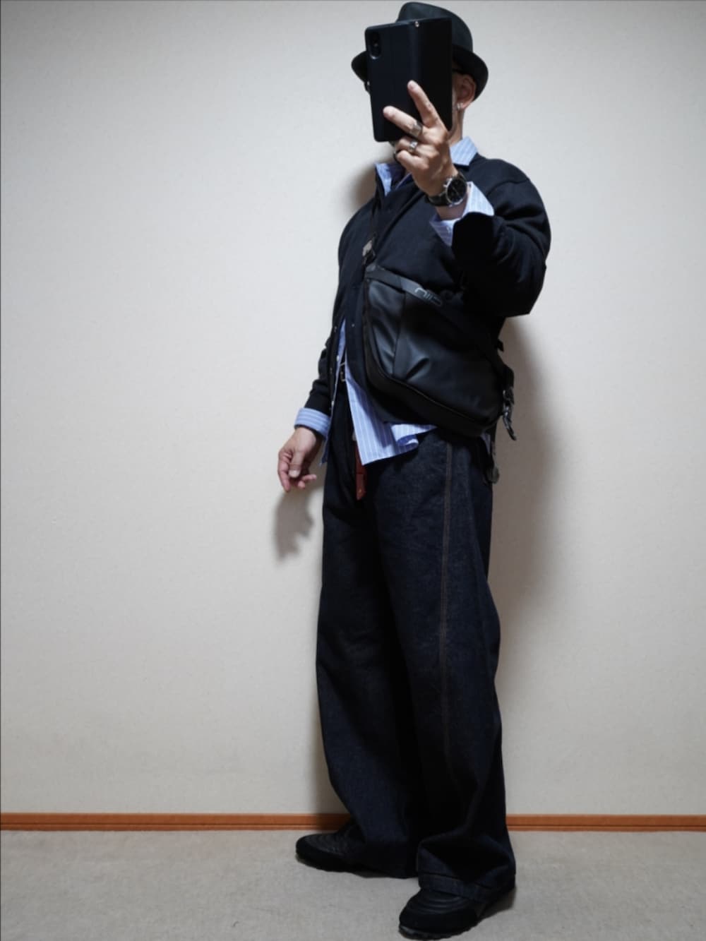 ブラック系のスニーカー、ブルー系のデニムパンツ、グレー系のシャツ/ブラウスを着用したメンズの秋コーディネートの2枚目の写真