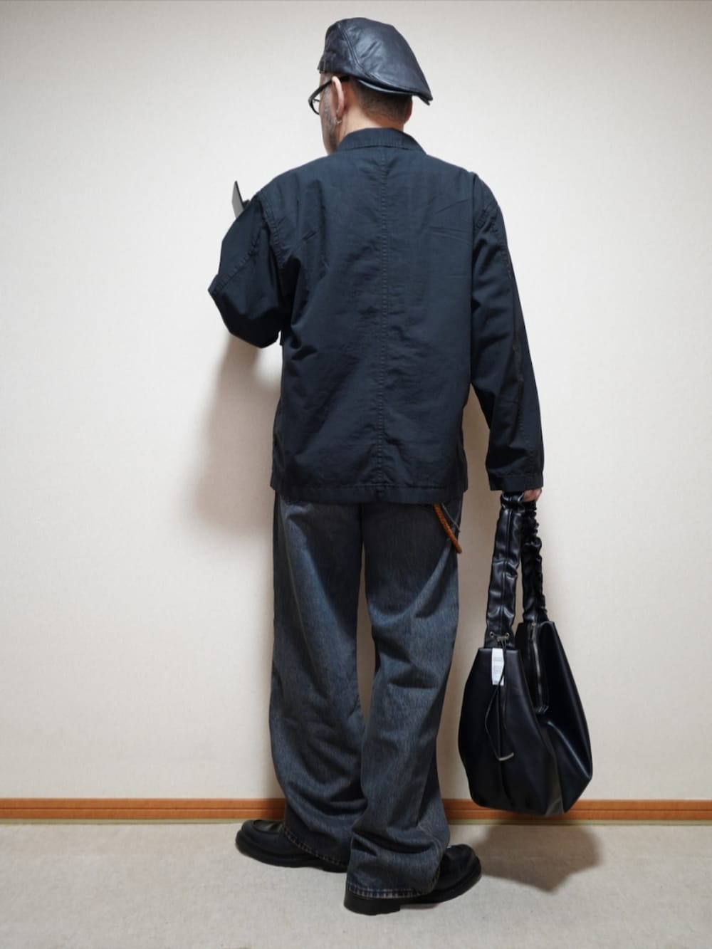 ブラック系のシューズ、ブルー系のデニムパンツ、ブラック系のショルダーバッグを着用したメンズの春コーディネートの4枚目の写真