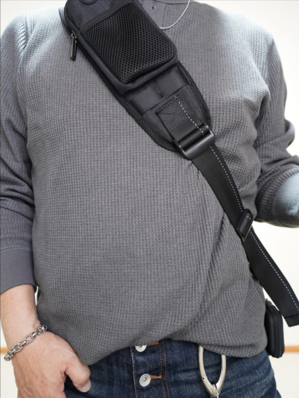 ブルー系のデニムパンツ、グレー系のTシャツ/カットソー、ブラック系のバッグを着用したメンズの秋コーディネートの3枚目の写真