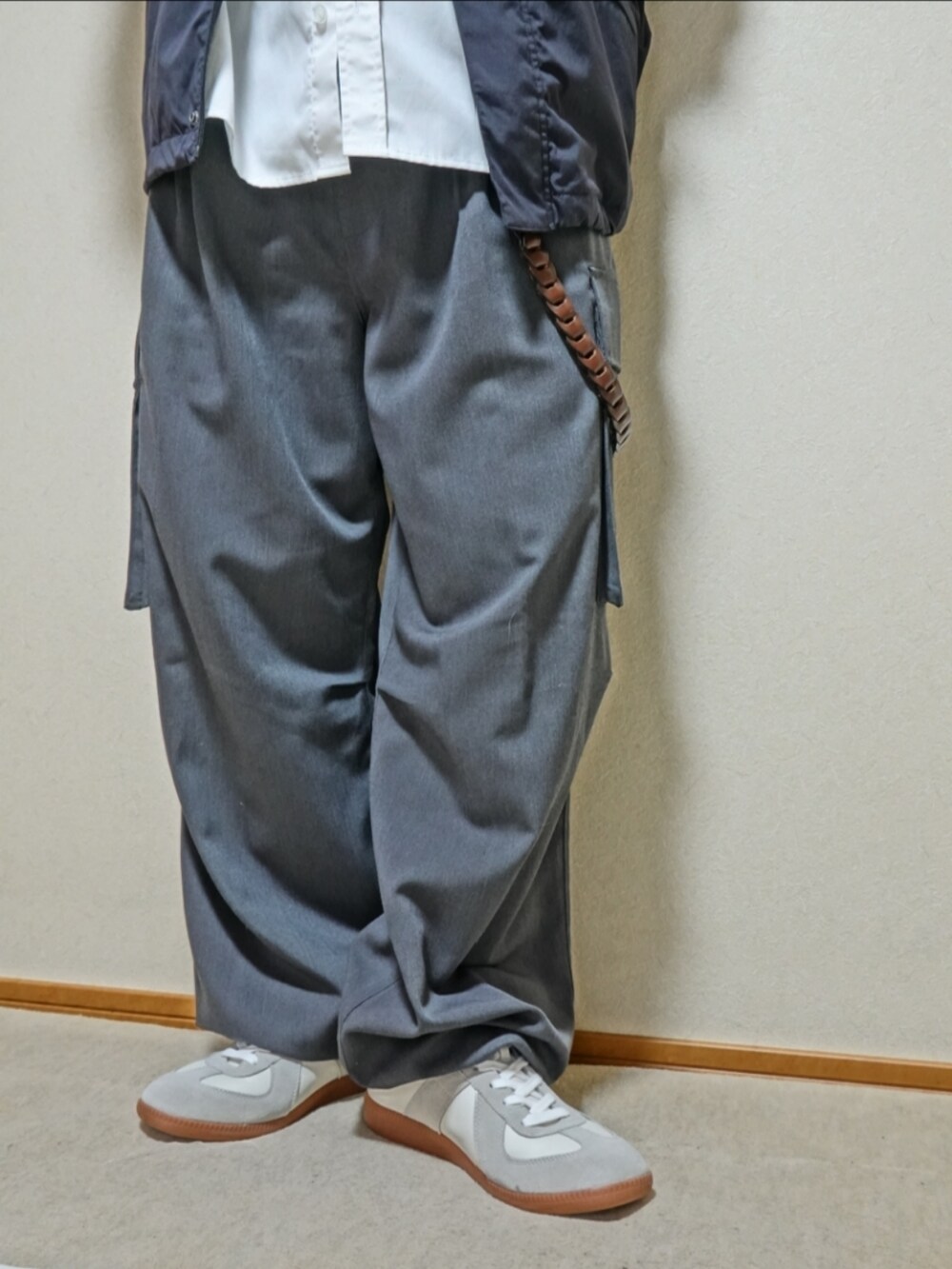 ホワイト系のスニーカー、グレー系のカーゴパンツ、ブラック系のショルダーバッグを着用したメンズの秋コーディネートの4枚目の写真