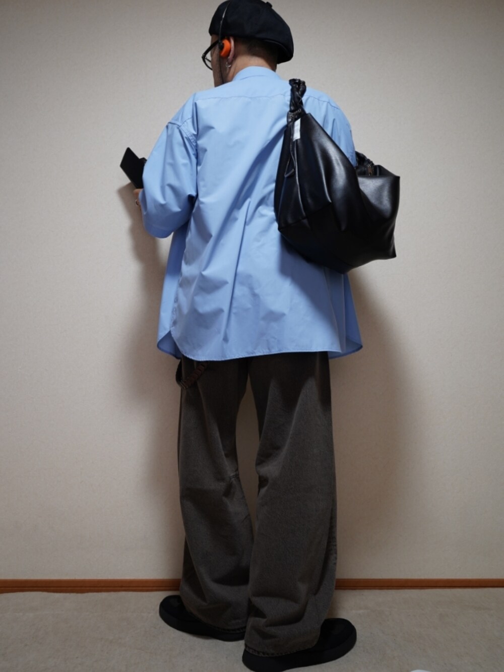 ブラック系のスニーカー、ブラウン系のデニムパンツ、ブラック系のショルダーバッグを着用したメンズの夏コーディネートの3枚目の写真